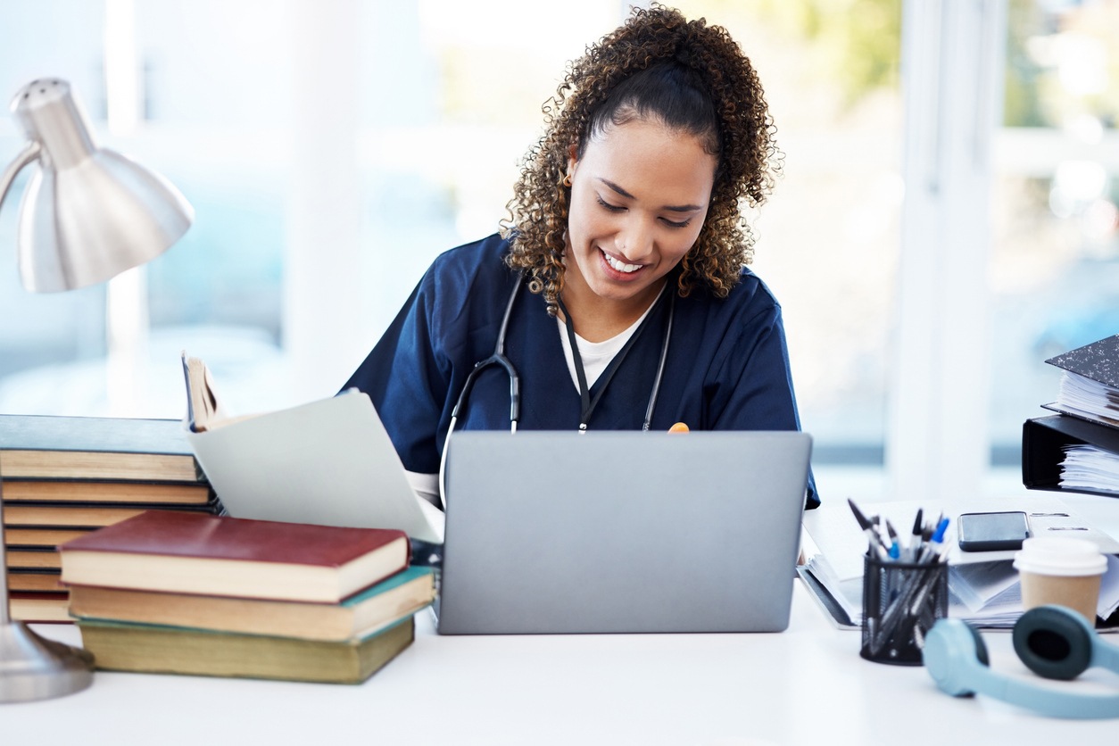 Nurse in Scrubs Smiling and Working on a Laptop..jpg Nurse in scrubs smiling and working on a laptop.